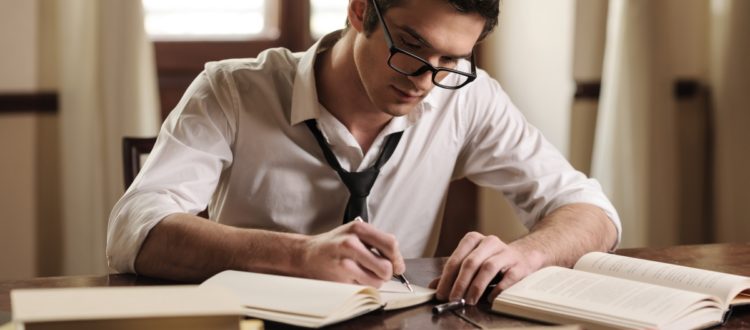 Un tânăr care stă la birou și scrie în agenda sa.